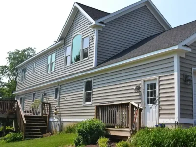 Side view of a gray house with white trim and wooden steps.