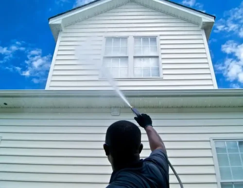 A person painting the exterior of a white house.