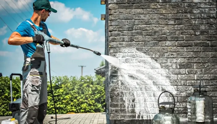 Worker pressure-washing exterior brick wall