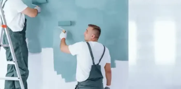 Two men painting a wall light blue.