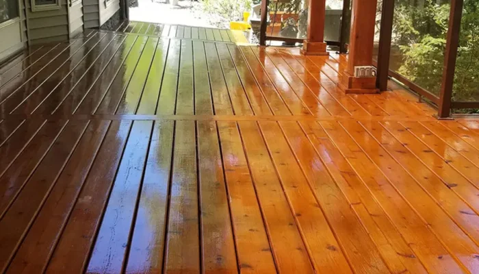 A wooden deck with half cleaned and half dirty surface.